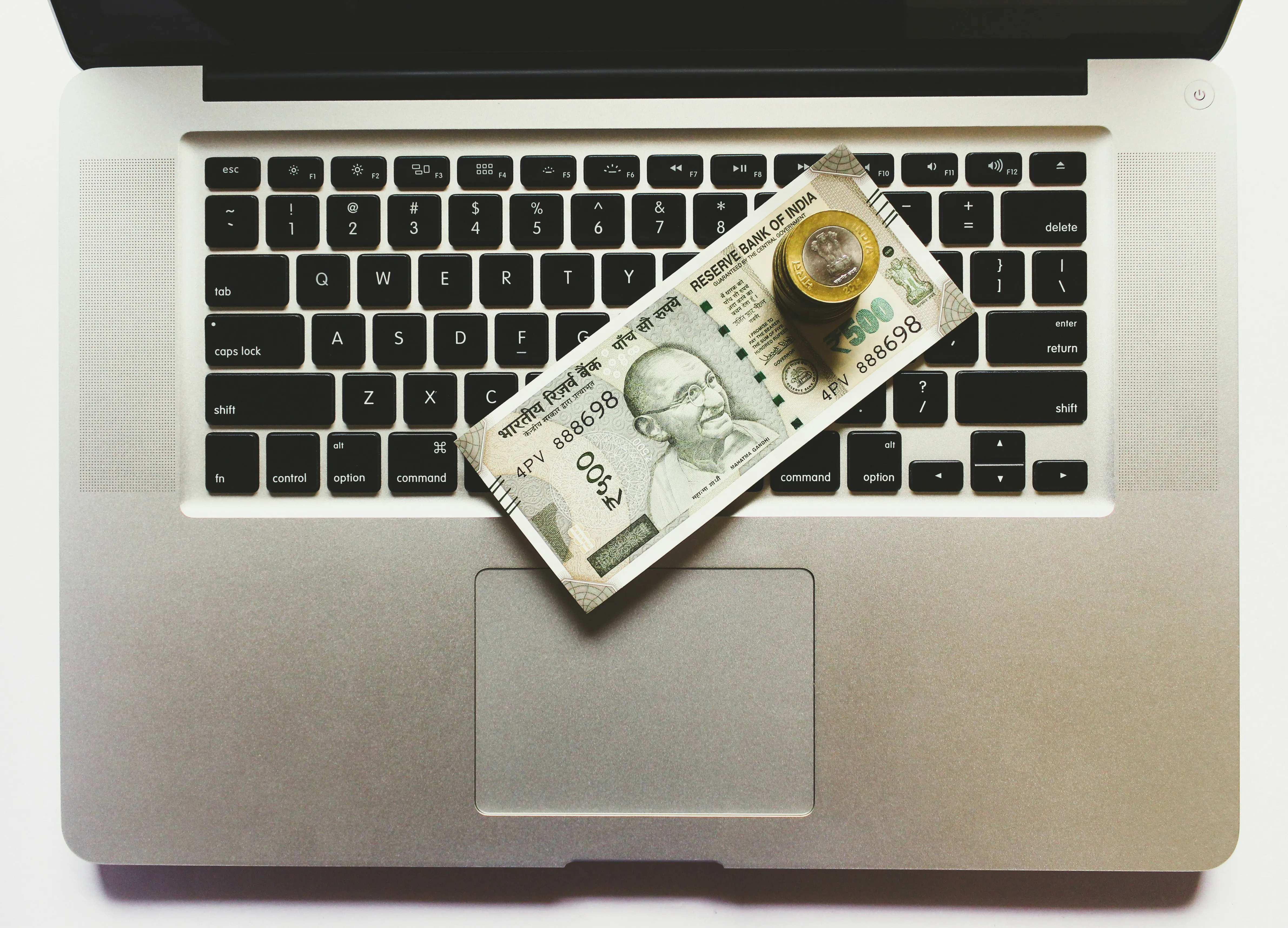 Laptop with currency and coins on keyboard.